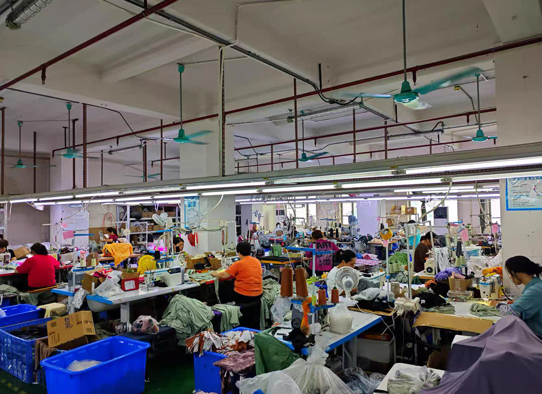 Wide view of an apparel sewing floor with workstations and operators